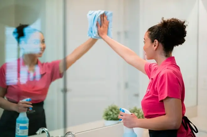 Cleaner wiping mirror with detail-focused checklist cleaning